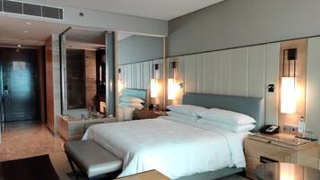Una habitación de hotel moderna con una cama grande, mesitas de noche, un escritorio y un espejo.