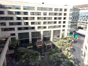 A multi-story building with a modern architectural design, featuring a mix of glass and concrete facades, and a landscaped courtyard with palm trees and a water feature. - JW Marriott Hotel New Delhi Aerocity (New Delhi)