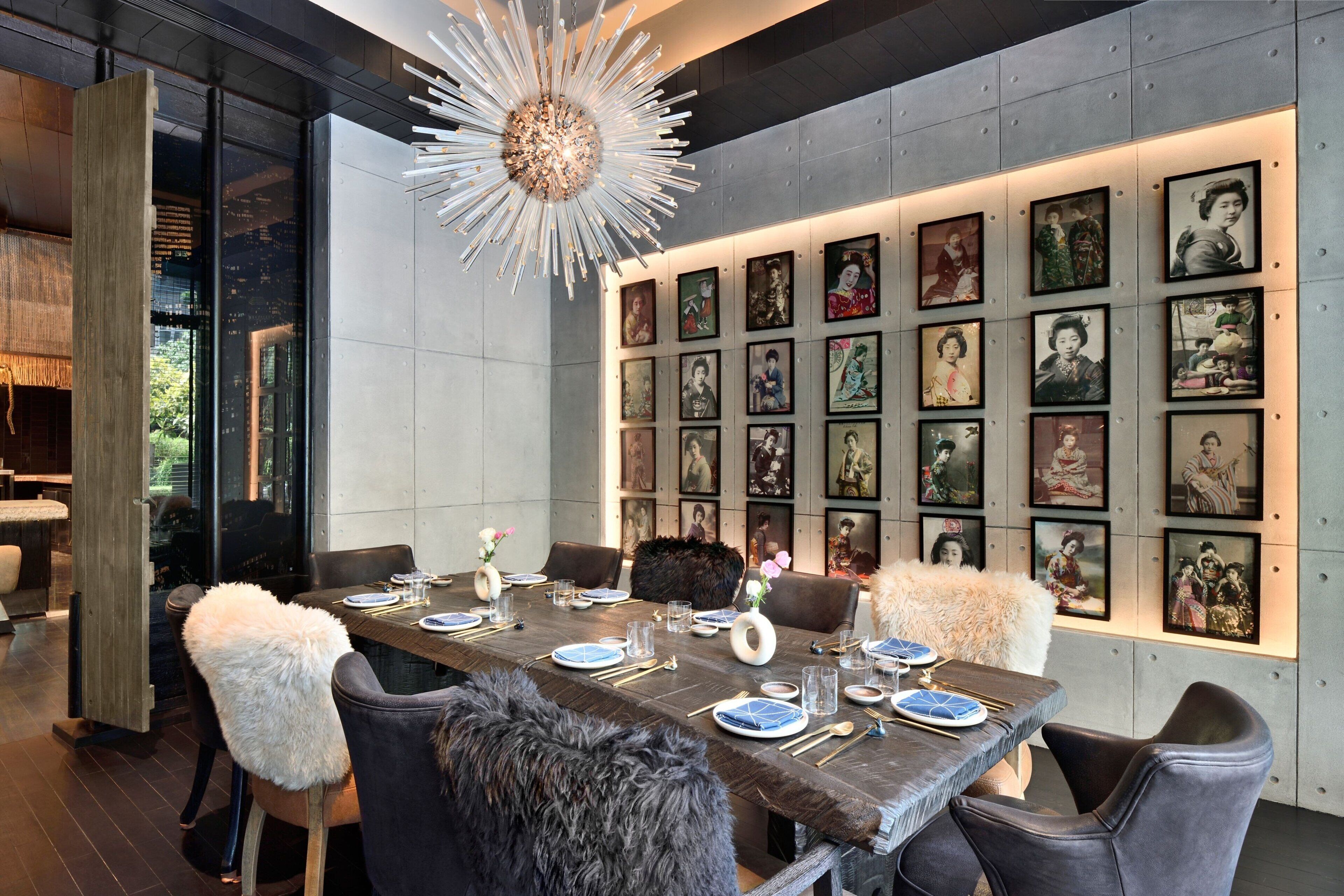 A modern dining area with a long table set for six, surrounded by plush chairs, and a wall adorned with framed artwork.