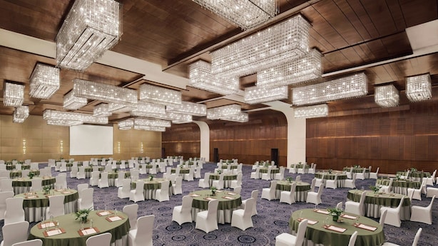 A large banquet hall with round tables, white chairs, and hanging crystal chandeliers. - JW Marriott Hotel New Delhi Aerocity (New Delhi)
