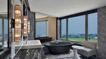 A modern bathroom with a large bathtub, a vanity with a mirror, and a view of the cityscape.