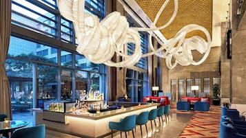 A modern bar area with a central island, seating, and large windows.