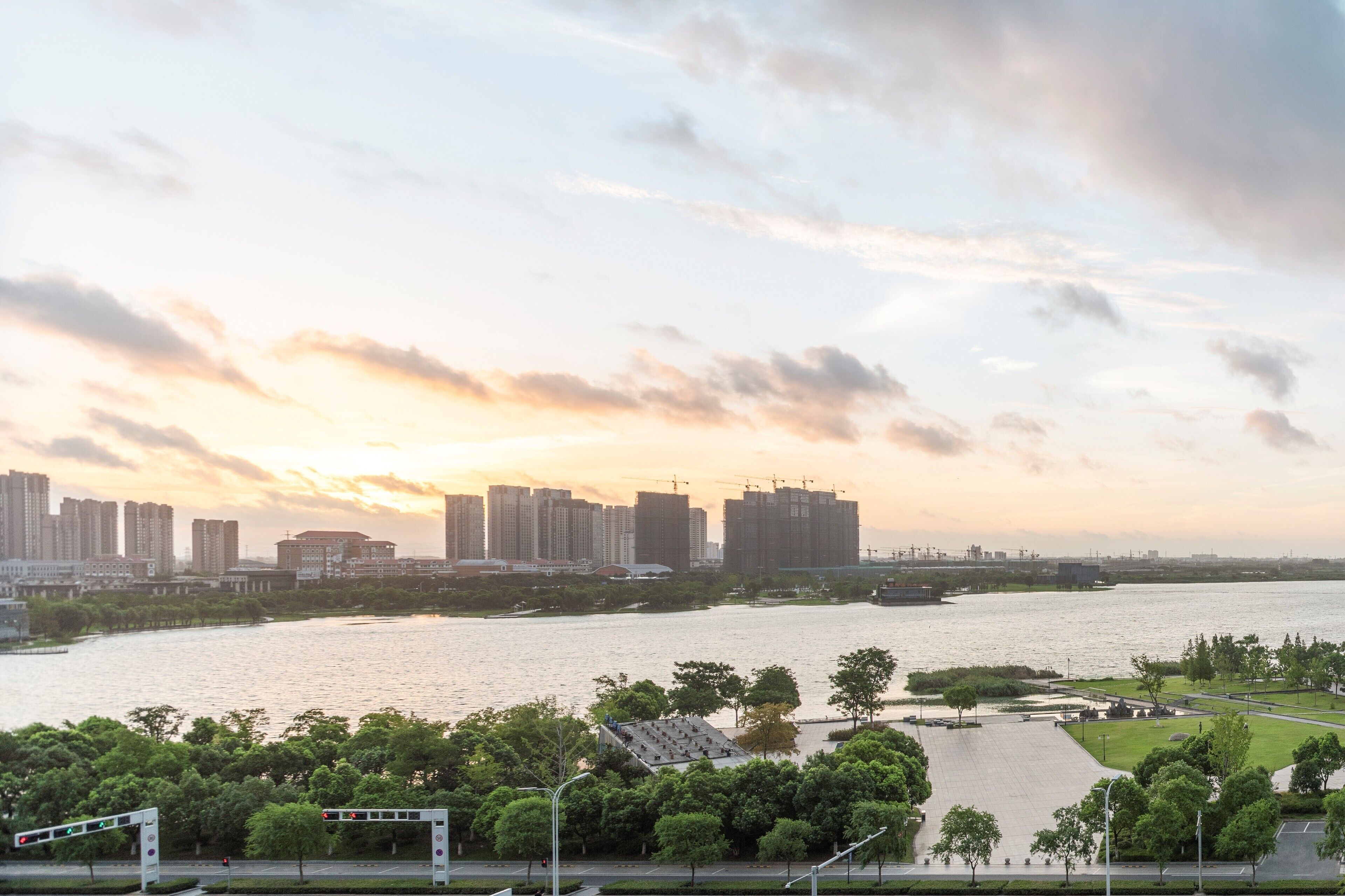 A river with a city skyline in the background, surrounded by greenery and a clear sky.