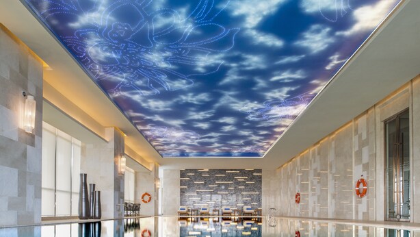 Una piscina interior moderna con un techo que simula un cielo estrellado.
