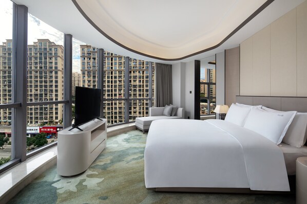 A modern hotel room with a large bed, a TV, and a view of high-rise buildings. - Holiday Inn Ningde Xiapu by IHG (Ningde)
