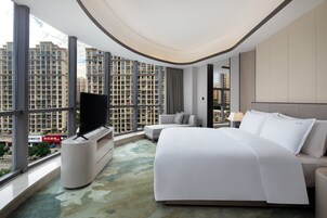Habitación de hotel moderna con una cama grande, televisión y vistas a rascacielos.