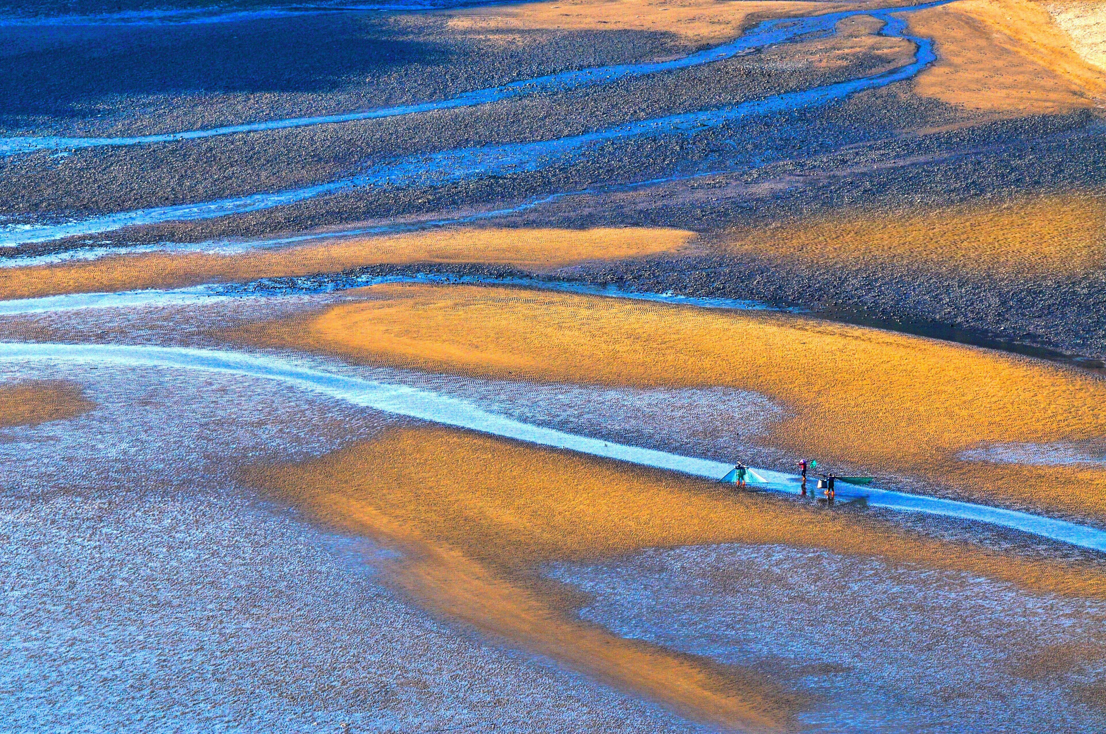 An aerial view of a winding road through a barren landscape with distinct orange and blue hues.