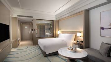 A hotel room with a bed, bedside table, lamp, and a TV.