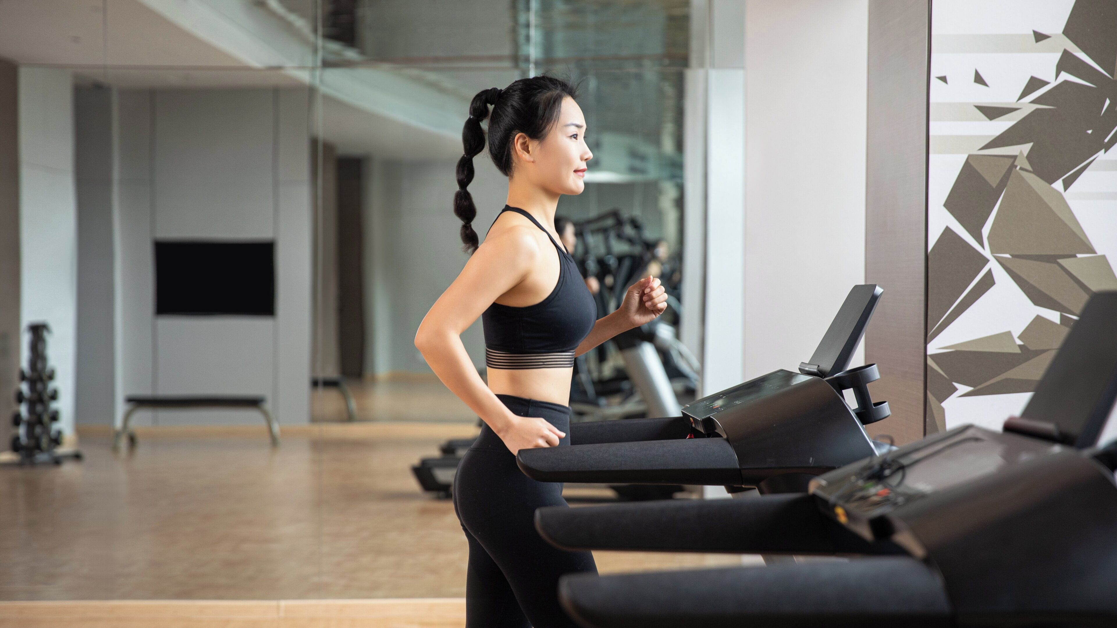 A gym interior with exercise equipment, a treadmill, and a mirrored wall.
