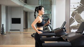 A gym interior with exercise equipment, a treadmill, and a mirrored wall.