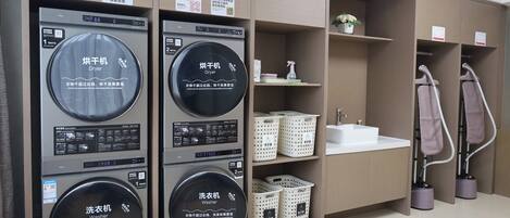A laundry facility with multiple washing and drying machines, a sink, and storage baskets.