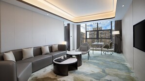 A modern hotel room with a grey sofa, two armchairs, a coffee table, and a TV. - Holiday Inn Ningde Xiapu by IHG (Ningde)
