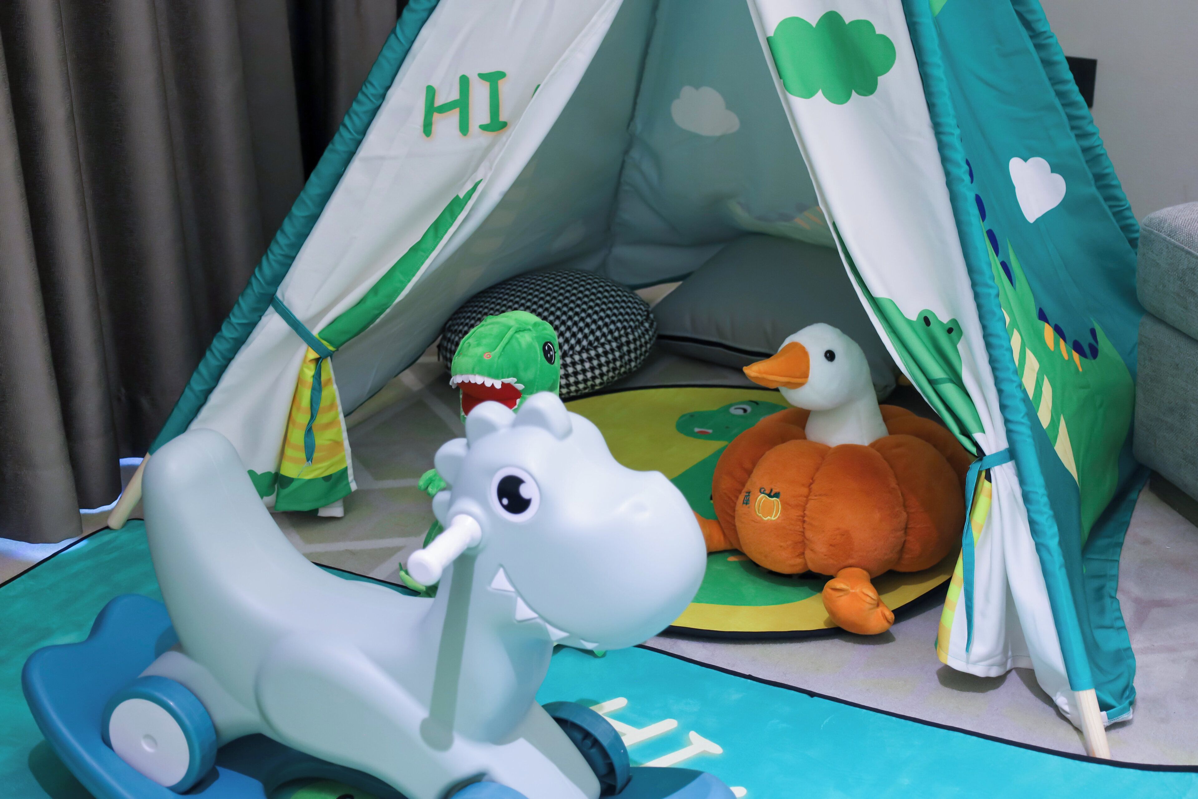 Een kinderspeeltent met een speelgoeddinosaurus, een eend en een pompoen erin.