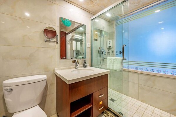 A bathroom with a toilet, sink, vanity, and a glass-enclosed shower. - Dunhuang International Hotel (Jiuquan)