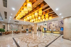 A spacious lobby with a modern chandelier, a reception desk, and a large abstract mural on the wall. - Dunhuang International Hotel (Jiuquan)