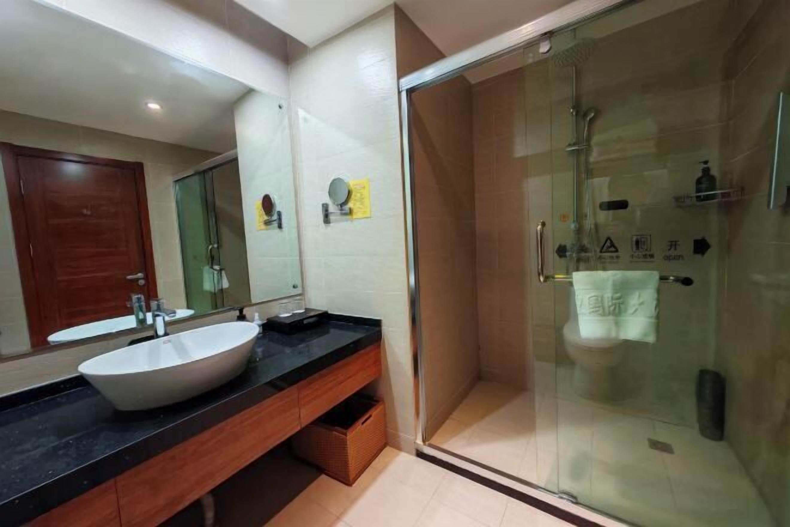 A modern bathroom with a large mirror, a white sink, and a glass-enclosed shower area.