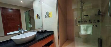 A modern bathroom with a large mirror, a white sink, and a glass-enclosed shower area.