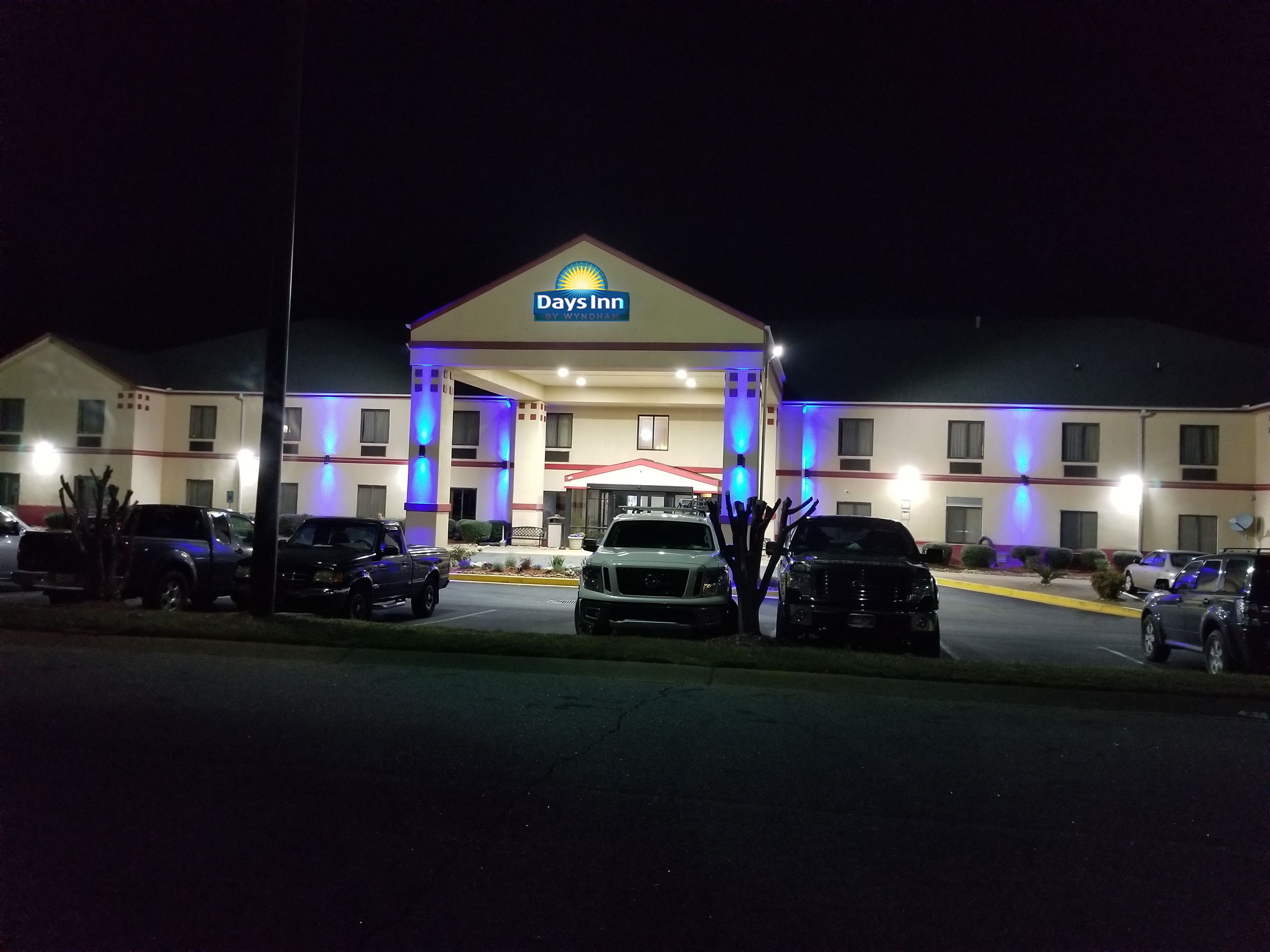 Um hotel Days Inn com entrada central, vários espaços de estacionamento e fachada bem iluminada.