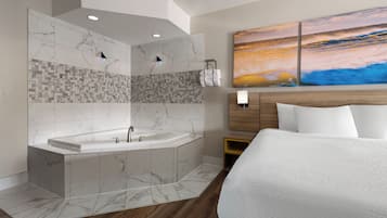 Habitación de hotel moderna con una cama grande, una bañera y una obra de arte colgada en la pared.