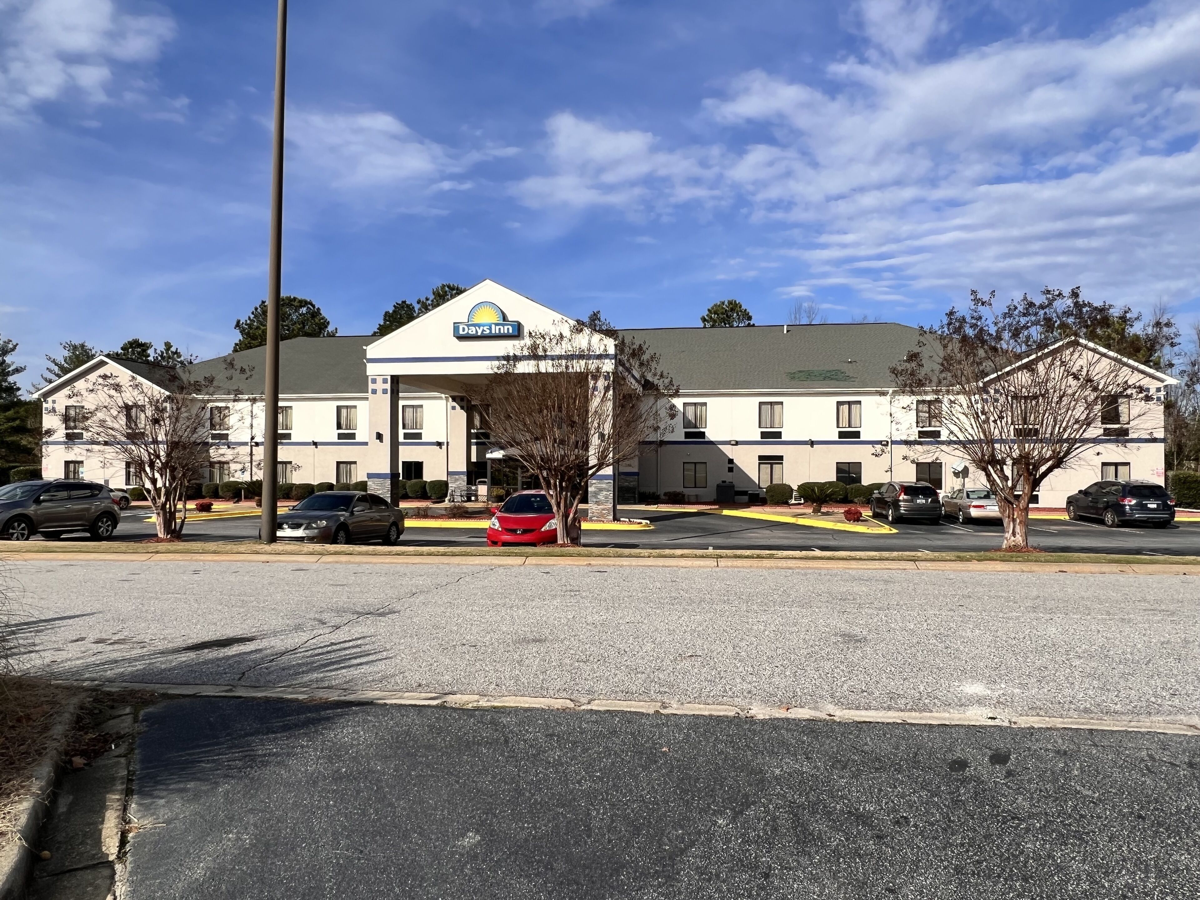 A Days Inn with a two-story building, a parking lot, and several cars parked in front.