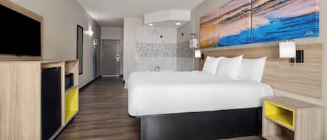 Ein modernes Hotelzimmer mit einem großen Bett, einem Fernseher, einem Badezimmer mit Dusche und einem Bild an der Wand.