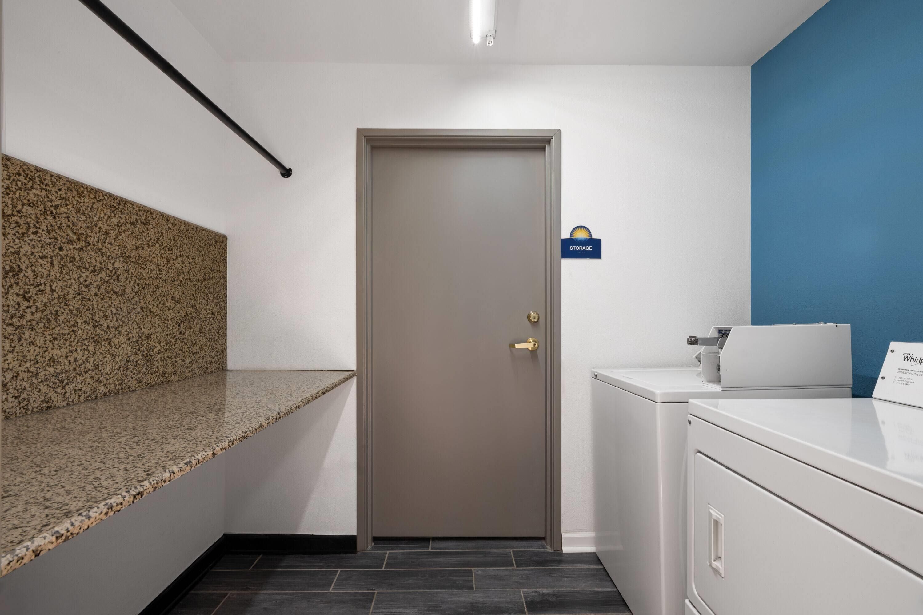 Une chambre d’hôtel avec une porte, un plan de travail, un lave-linge et un mur bleu.