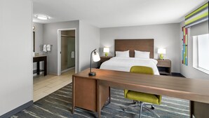 Habitación de hotel con cama, escritorio, silla, lámparas de noche y un ventanal grande.