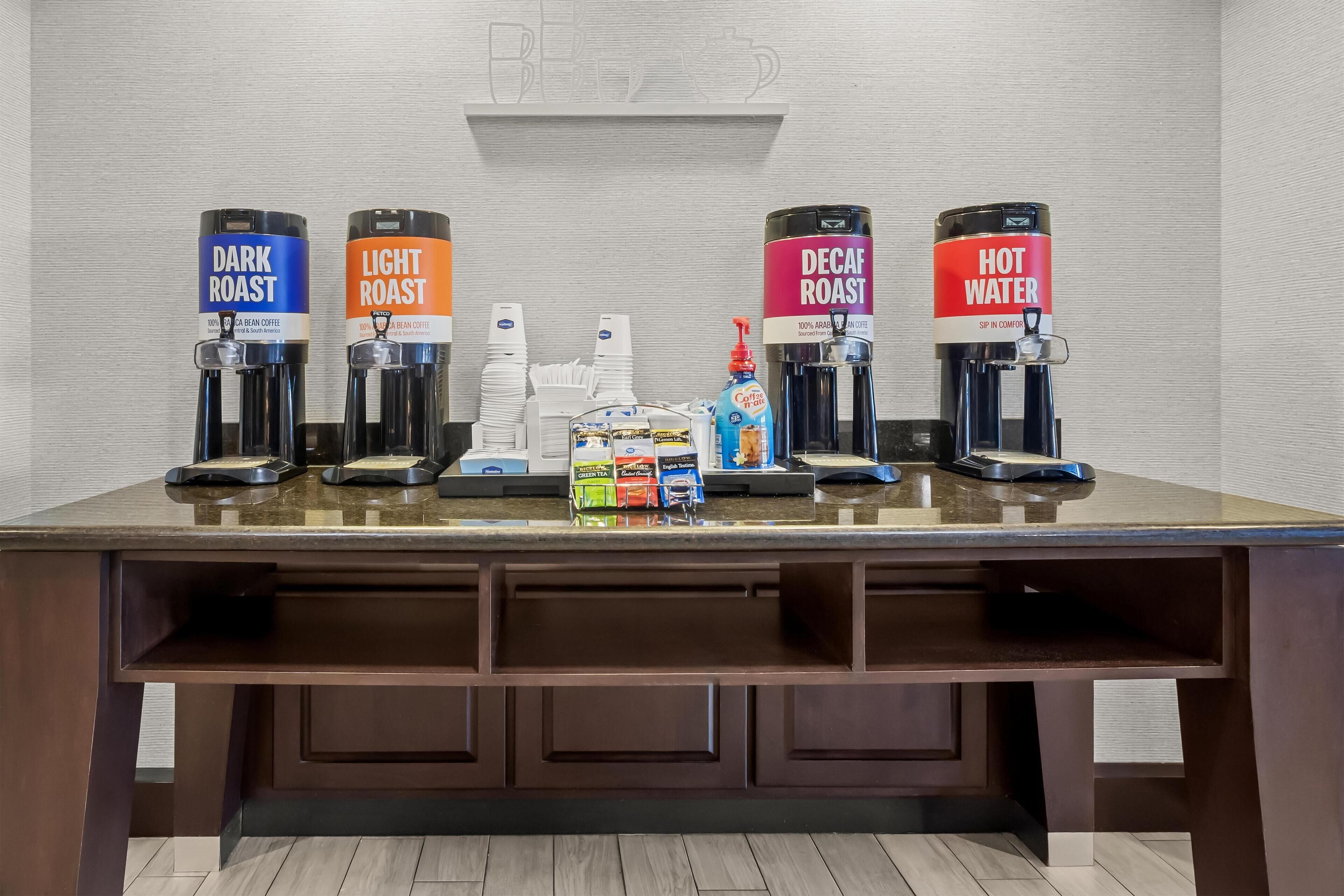 A coffee station with four coffee dispensers labeled Dark Roast, Light Roast, Decaf Roast, and Hot Water.