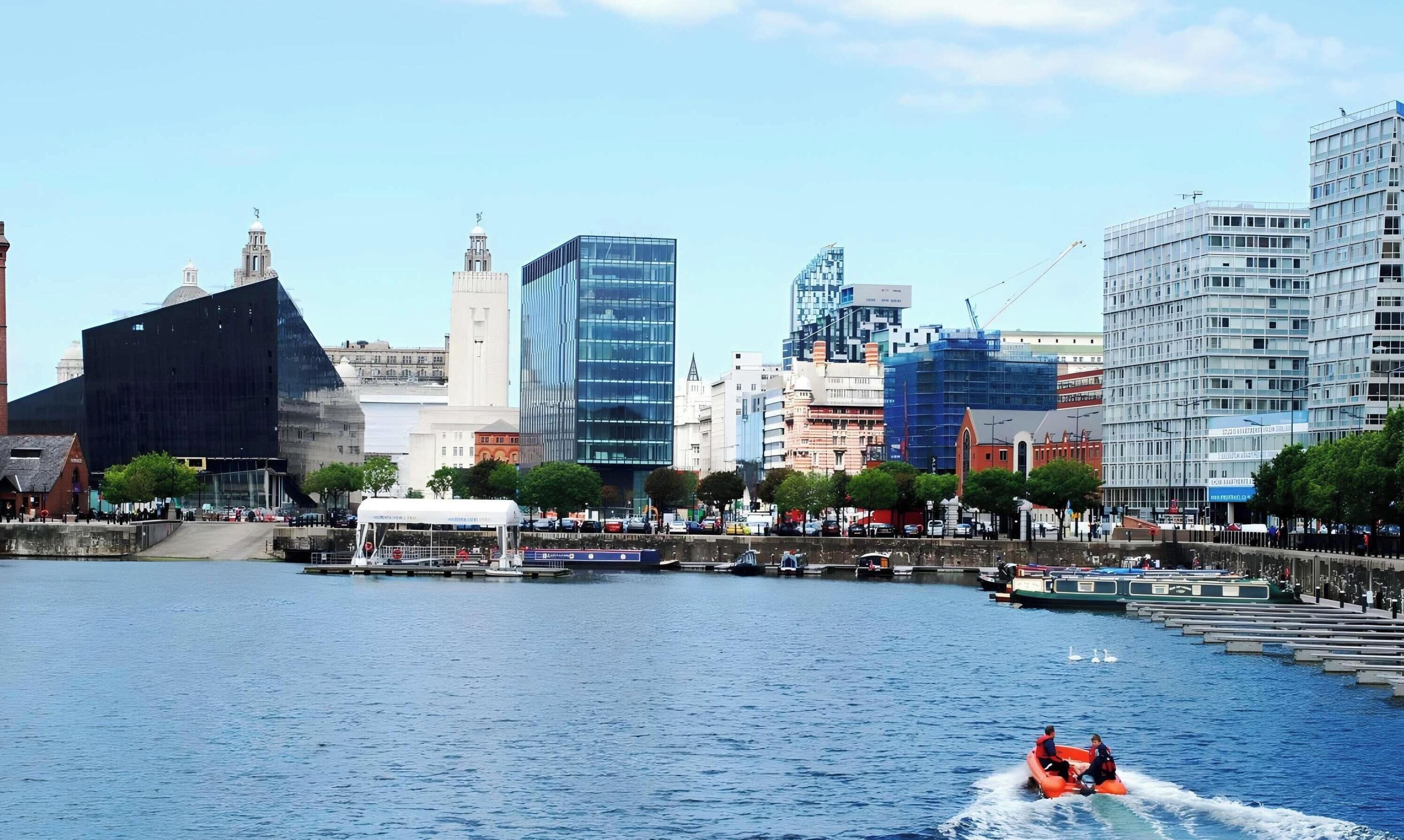 A cityscape with modern buildings, a waterfront, and a boat with people.