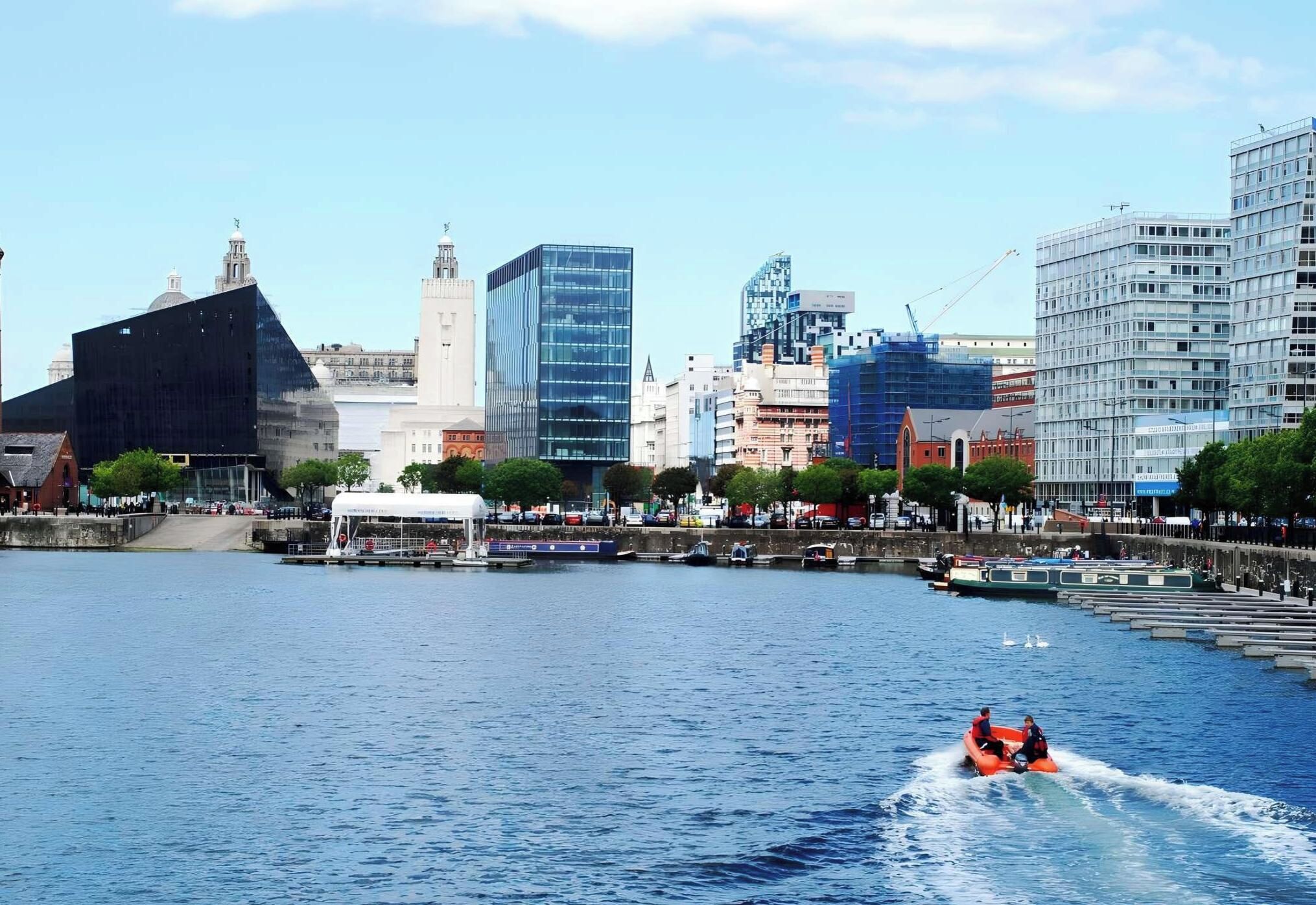 Un paisaje urbano frente al agua con edificios modernos, un río y un bote con pasajeros.
