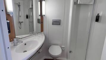 A modern bathroom with a white sink, mirror, and toilet.