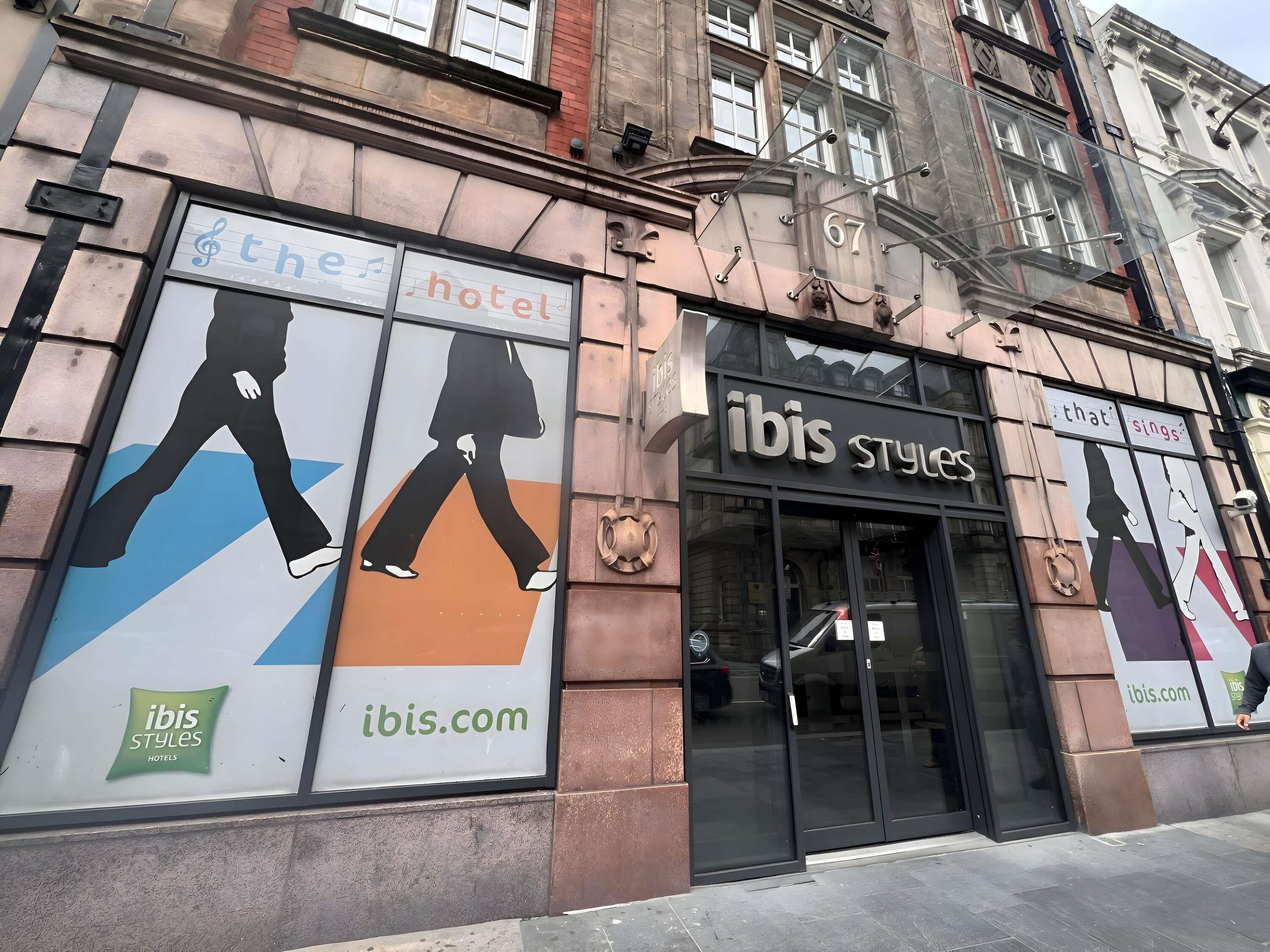 A building with a sign for 'The Hotel ibis Styles' and 'ibis Styles Hotels.'
