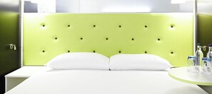 A bed with a green headboard, white pillows, and a bedside table with glasses and bottles. - ibis Styles Liverpool Centre Dale Street (Liverpool)