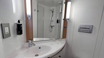 Ein modernes Badezimmer mit Waschbecken, Spiegel und Toilette in Weiß.