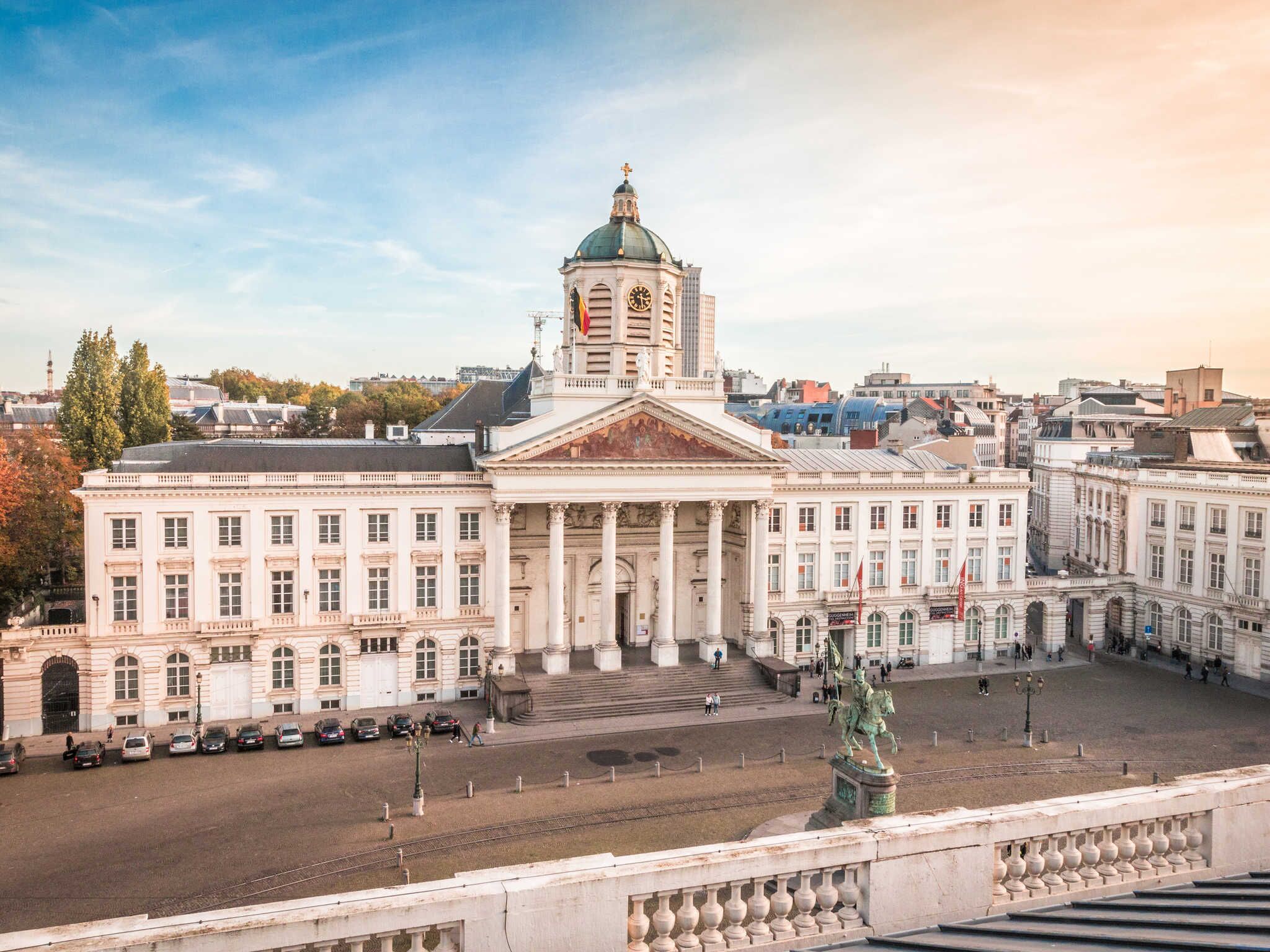 A large, classical building with a prominent dome and columns, situated in an urban setting with a wide plaza in front.