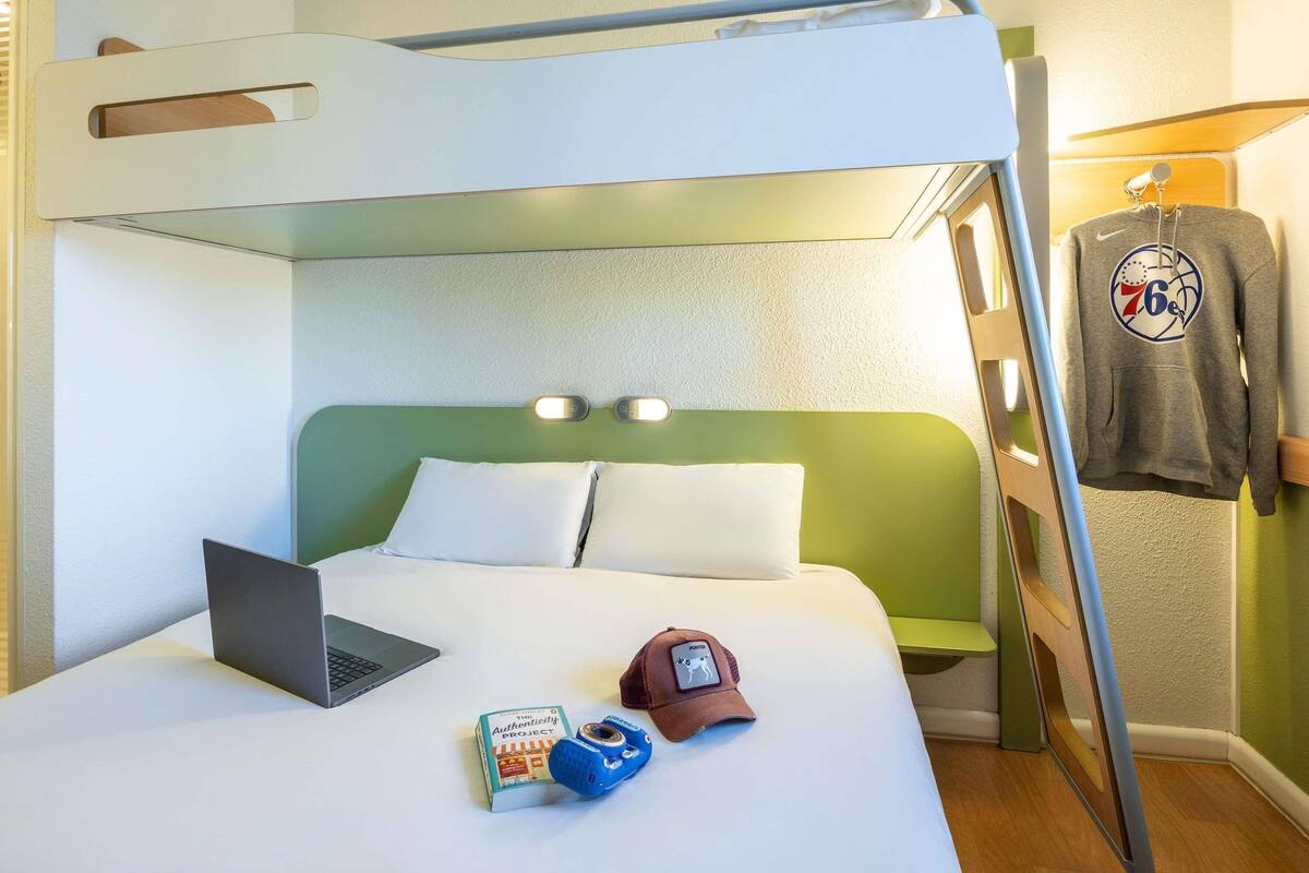 A bunk bed with a laptop, a book, a cap, and a hoodie on the side.