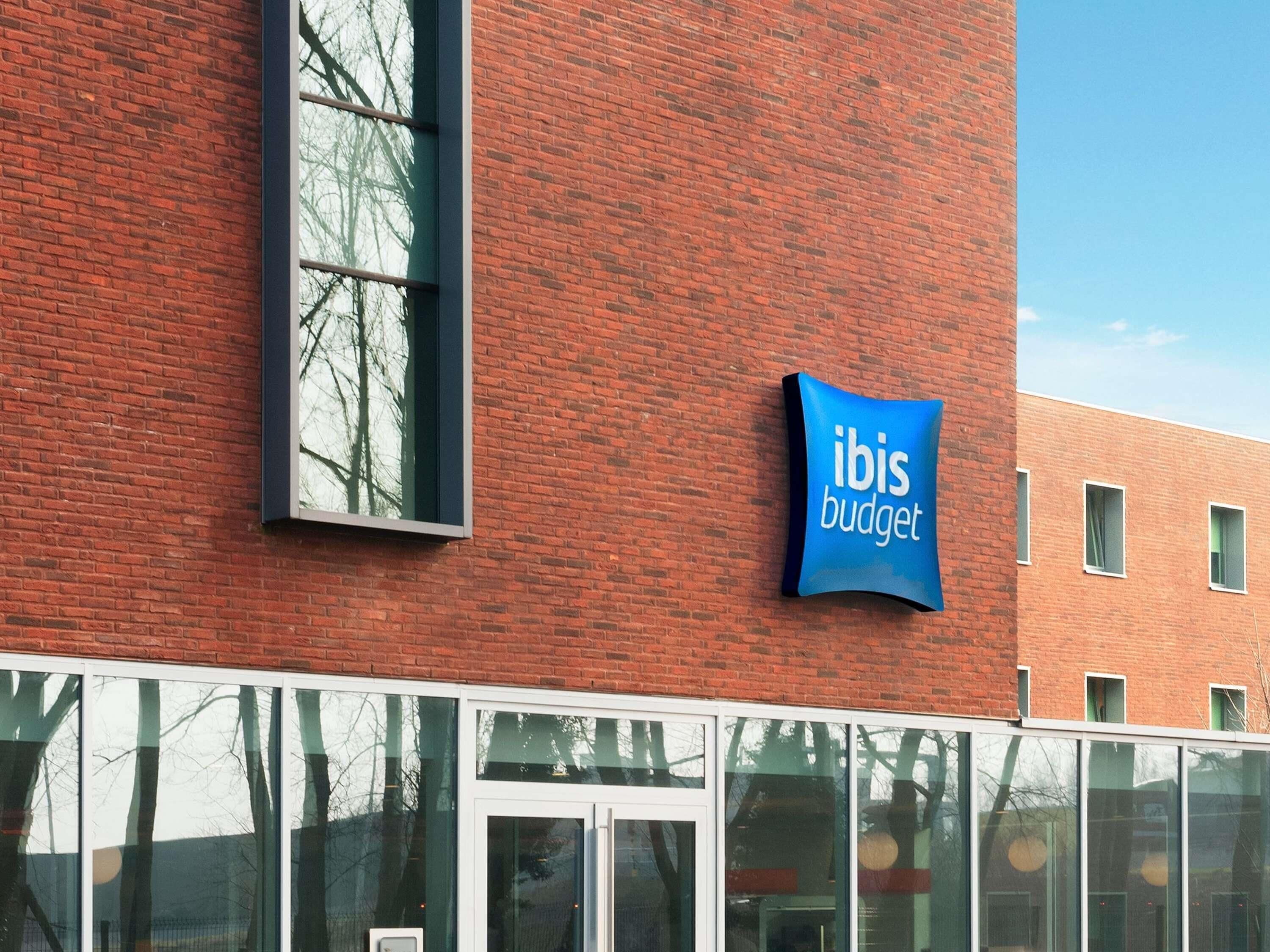 Un edificio con fachada de ladrillo rojo, un ventanal grande y un letrero que dice 'ibis budget'.