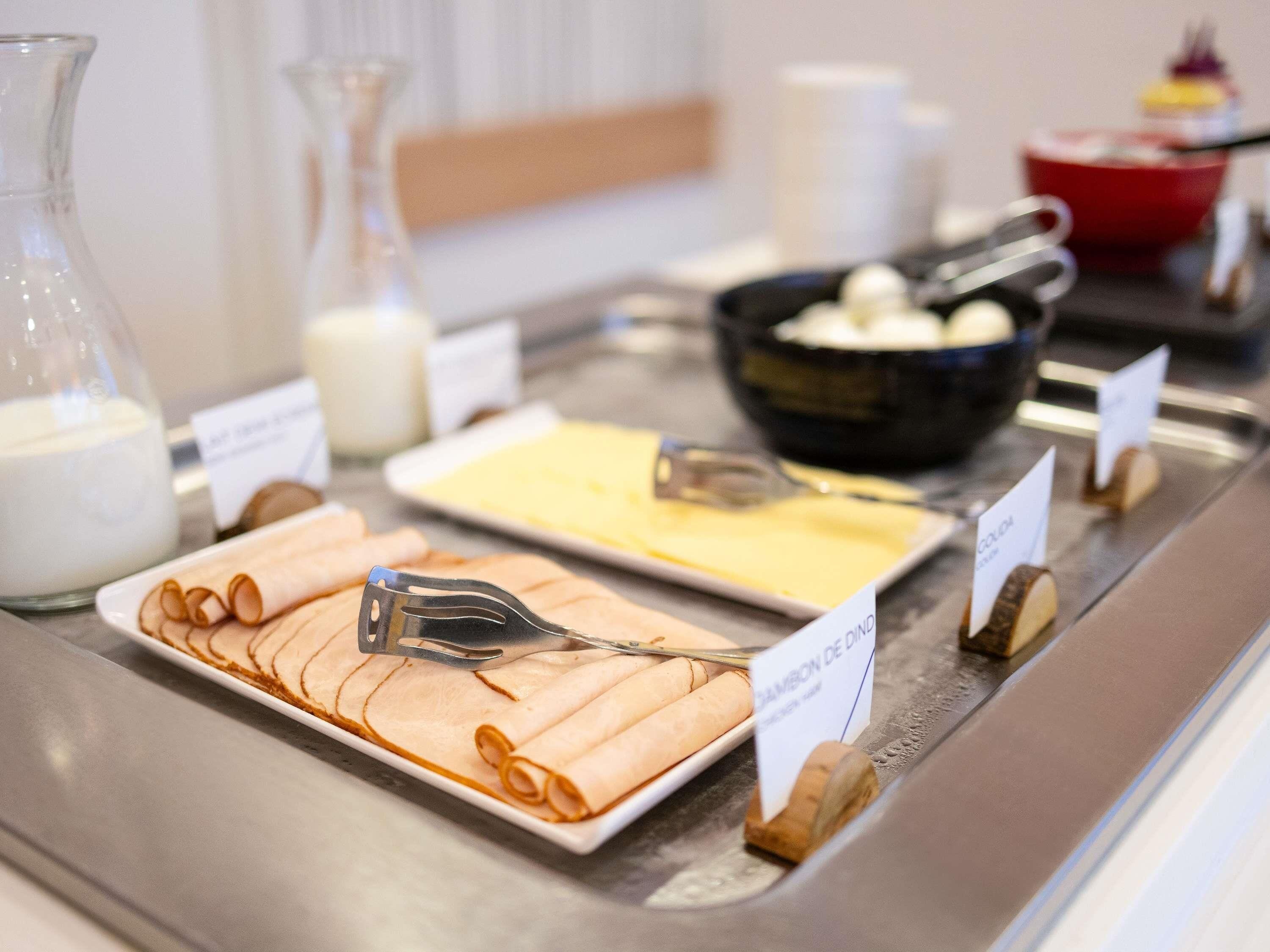 Een buffet met diverse gerechten, waaronder een schotel met de naam 'CHAMBON DE DIAMOND' en een kom die lijkt op yoghurt of een ander zuivelproduct.