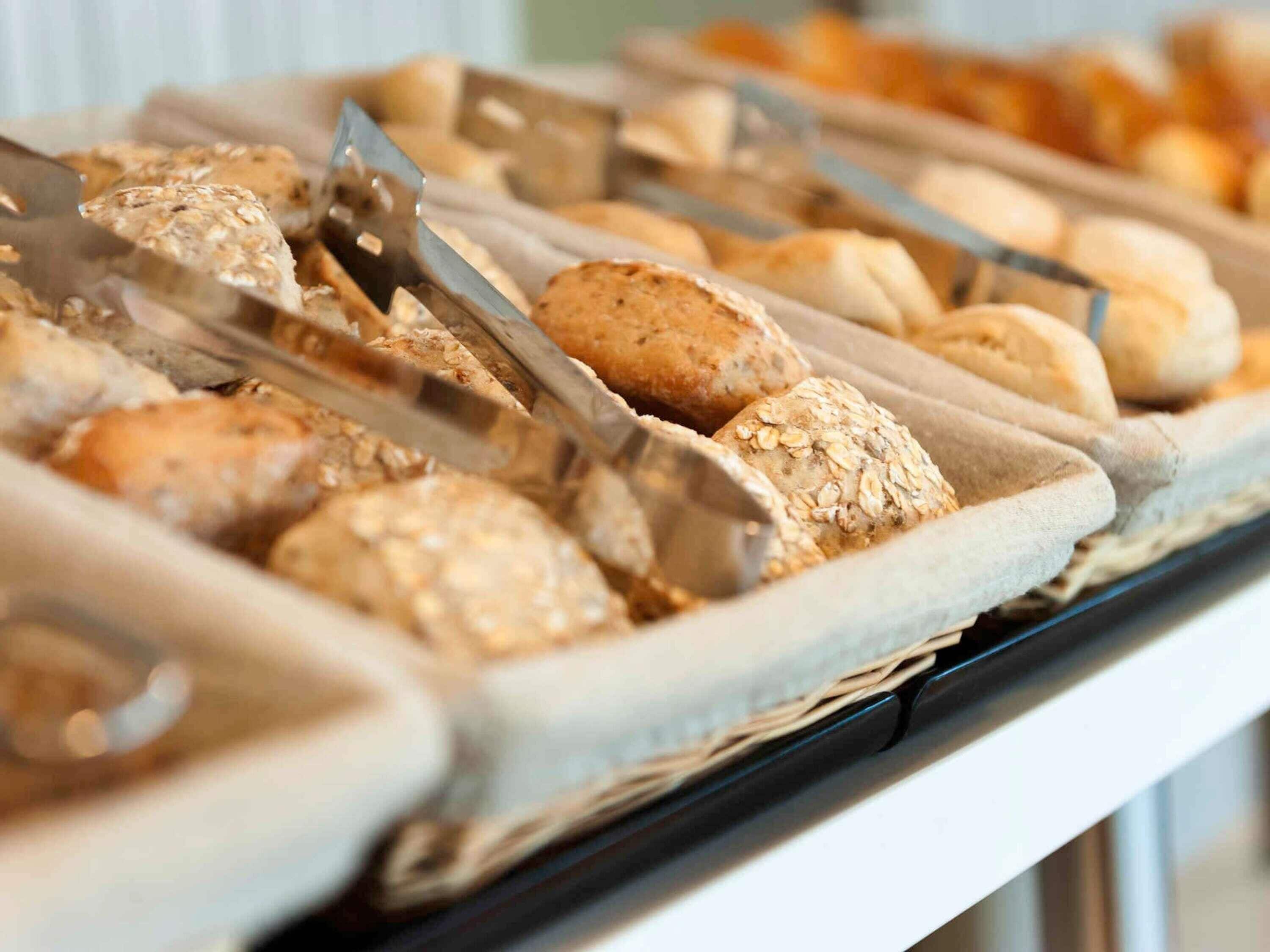 A buffet with various baked goods, including bread and pastries, arranged on trays.