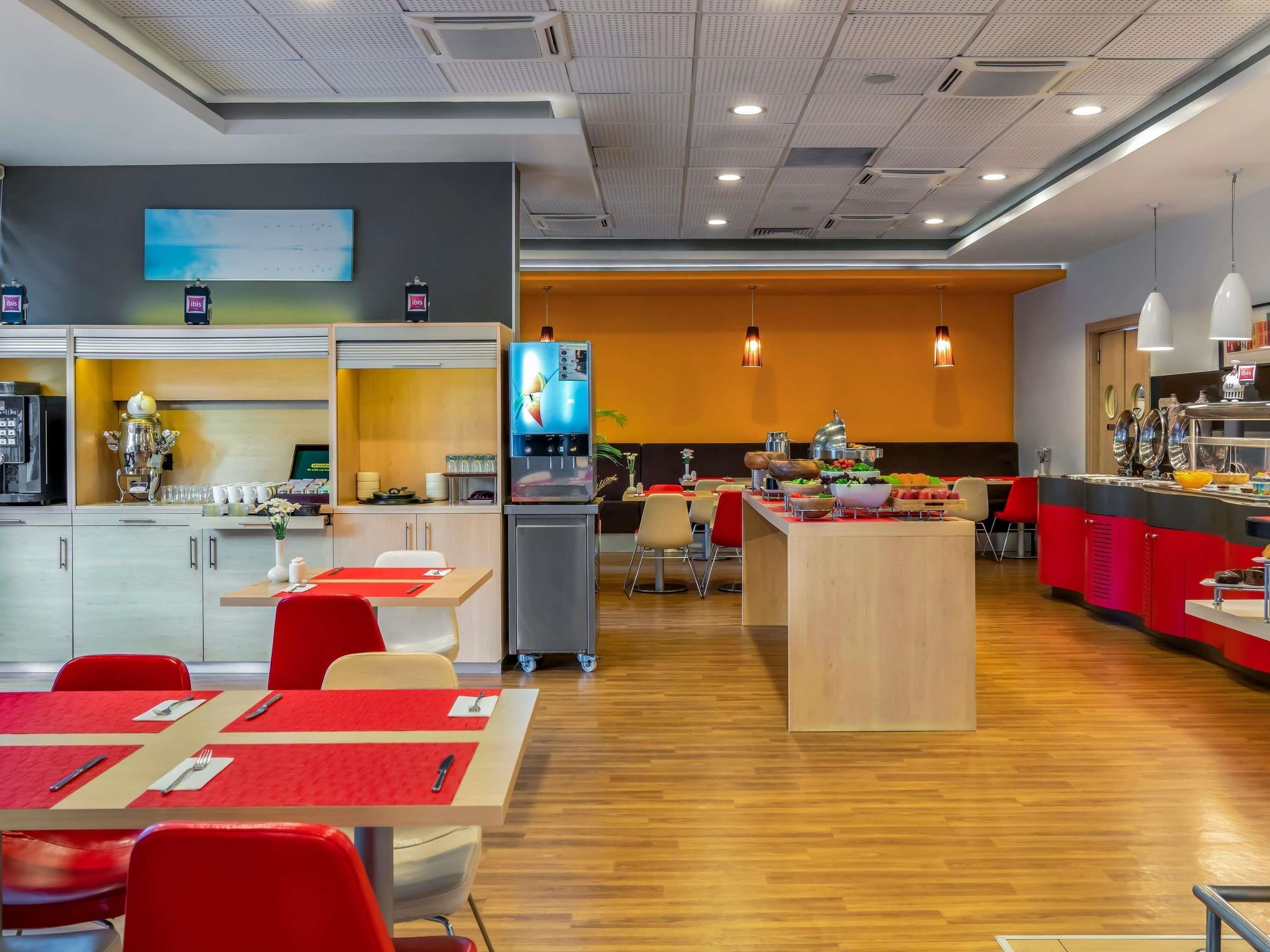A modern hotel lobby with a coffee machine, seating area, and a buffet.
