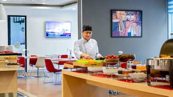 Um chef prepara comida em uma cozinha moderna com sistema de buffet.