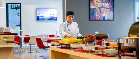 Een kok bereidt eten in een moderne keuken met een buffetopstelling.