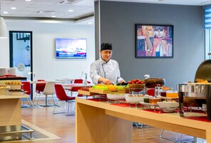 Um chef prepara comida em uma cozinha moderna com sistema de buffet.