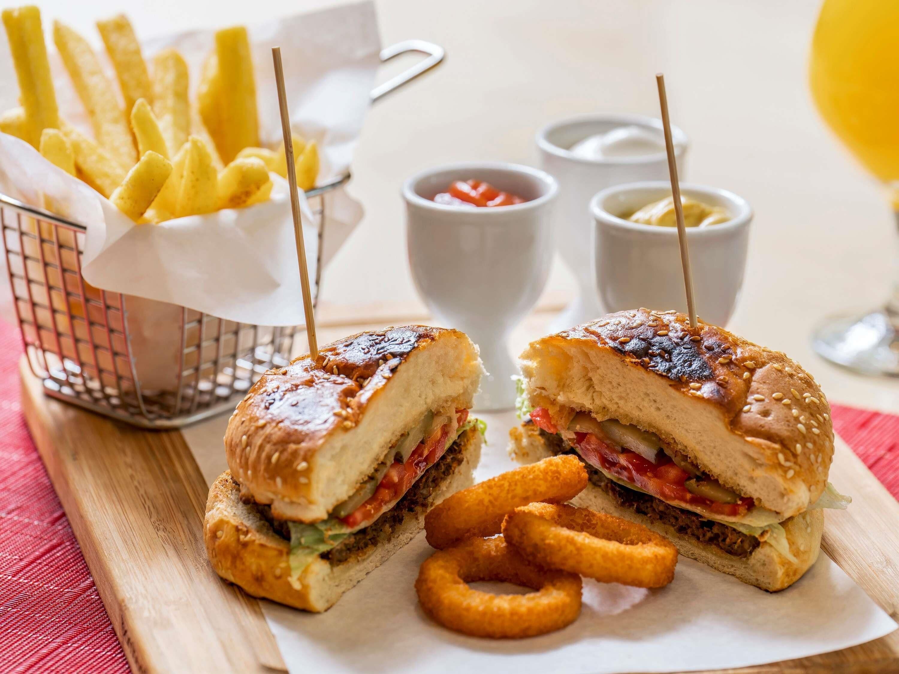 Un sandwich coupé en deux, accompagné d’une portion de frites et de sauces pour tremper.