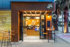 A cafe with a modern design, featuring a wooden facade, a black and white patterned floor, and a sign that reads "Cafe Walk inn".