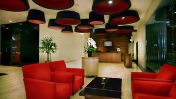 A modern lobby with red sofas, a reception desk, and a potted plant.