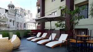 A rooftop lounge with sun loungers and tables, surrounded by a low wall and potted plants. - Atria Residences Gading Serpong (Gading Serpong)