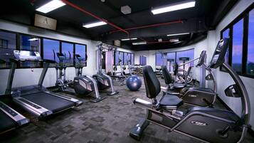 Un gimnasio con cintas de correr, elípticas y equipo de pesas.