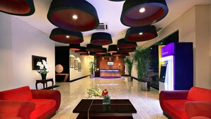 A modern lobby with red sofas, a black coffee table, and a reception desk. - Atria Residences Gading Serpong (Gading Serpong)