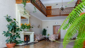 A spacious living room with a fireplace, wooden flooring, and a staircase leading to an upper level. - Pensjonat Halny (Zakopane)